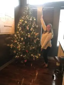 girl standing next to christmas tree with ornaments 