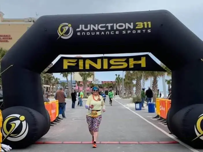 lady in yellow shirt crossing finish line