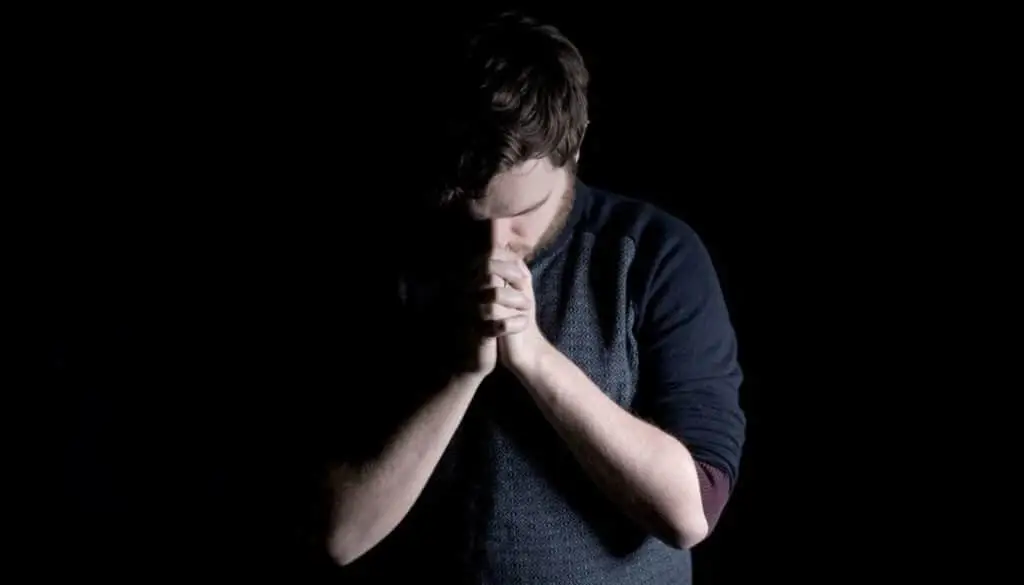 Man bowing in worship with hands clasped