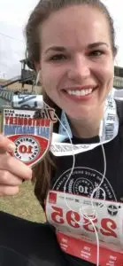 Miranda holding her medal from the 2019 Montgomery Half Marathon