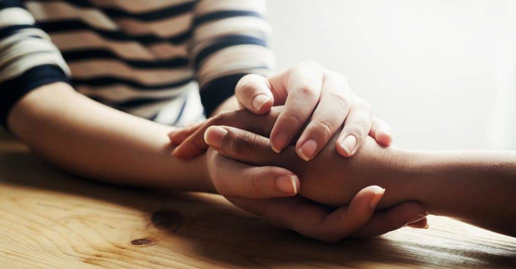 two people comfortingly holding hands