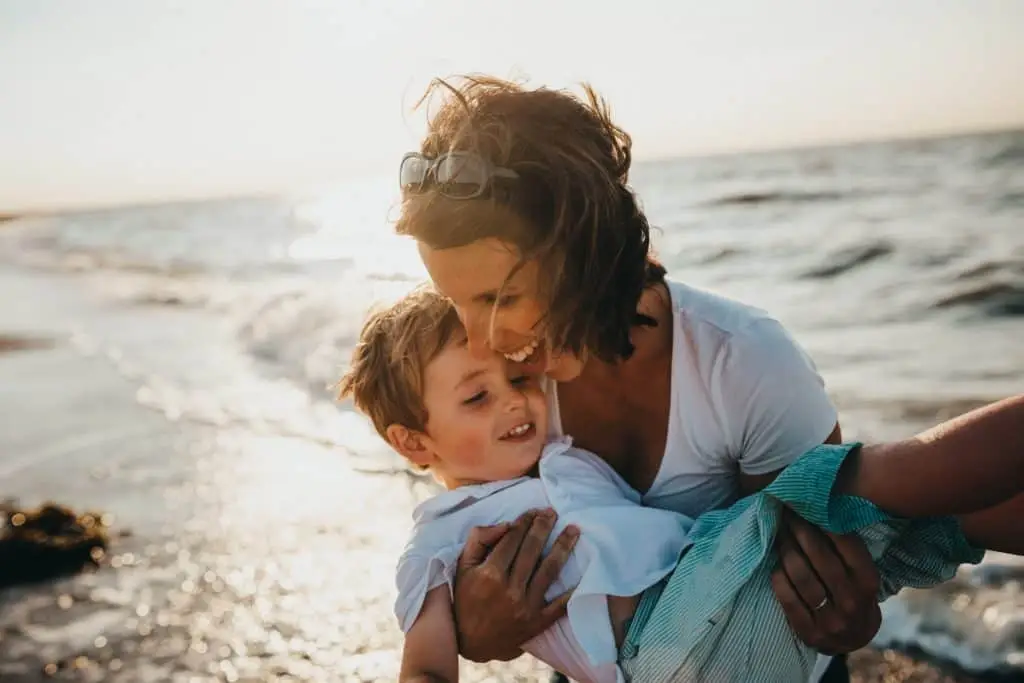 mom holding son on beach