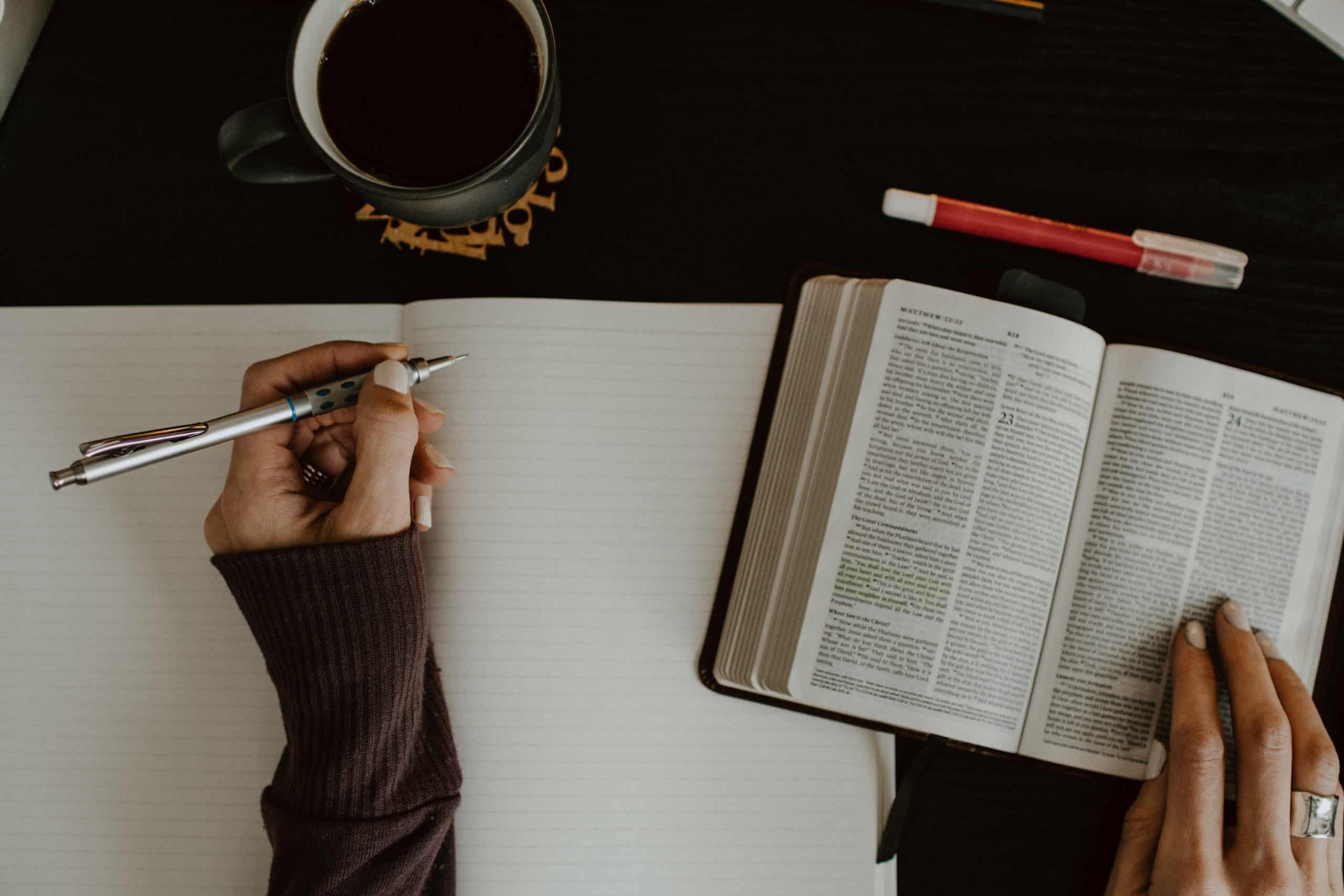 overhead shot of woman studying bible with notebook and pen