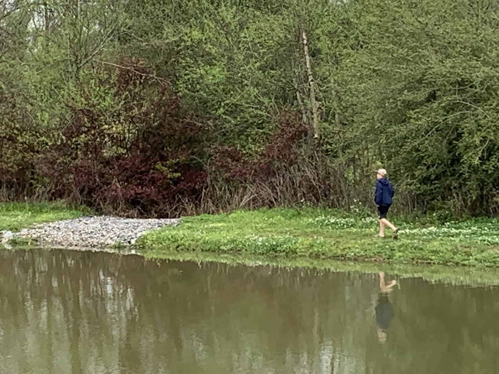 boy walking along banks of pond