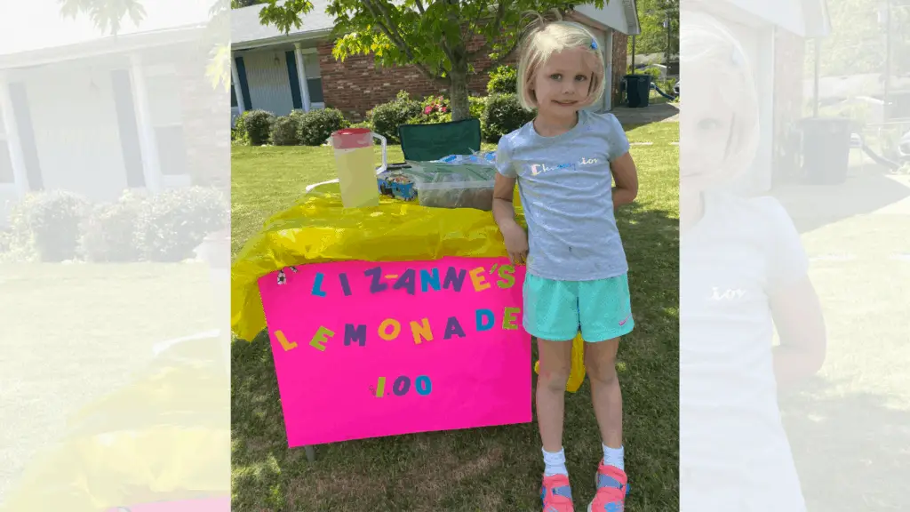 young girl in front of homemade lemonade stand