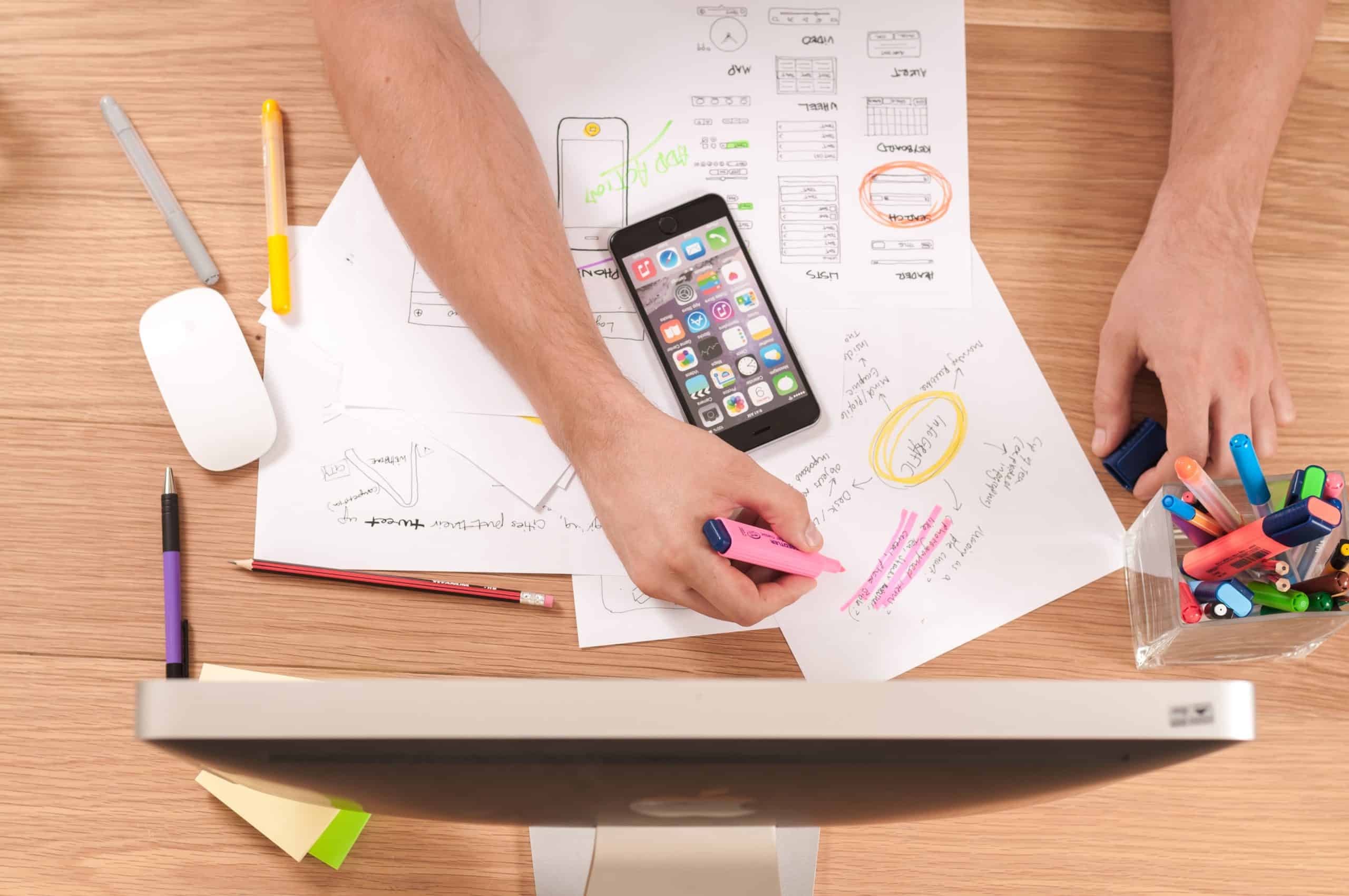 overhead shot of person highlighting notes on desk in front of computer