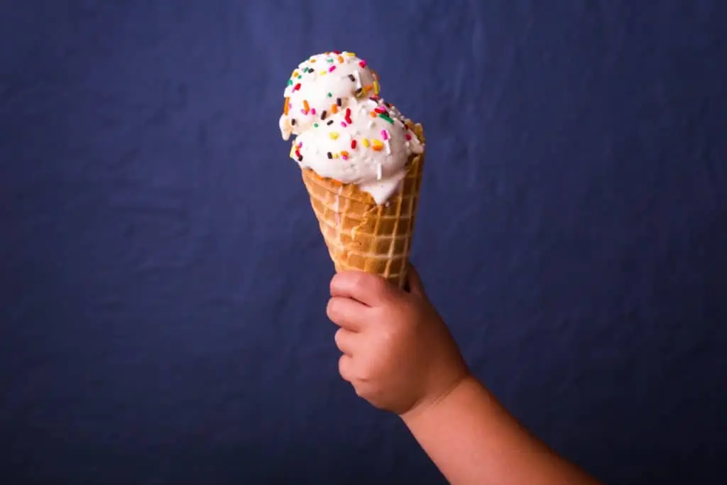 child holding ice cream cone in front of navy wall