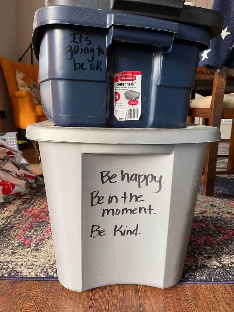 plastic bins labeled with positive notes to help pack away holiday decor