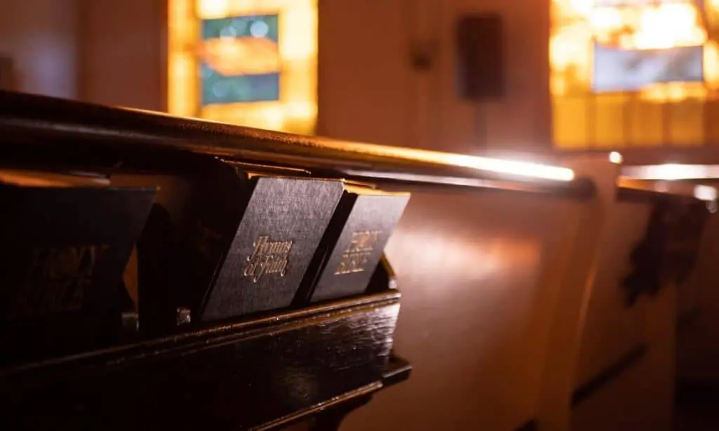 back of church pew with bibles and hymnals