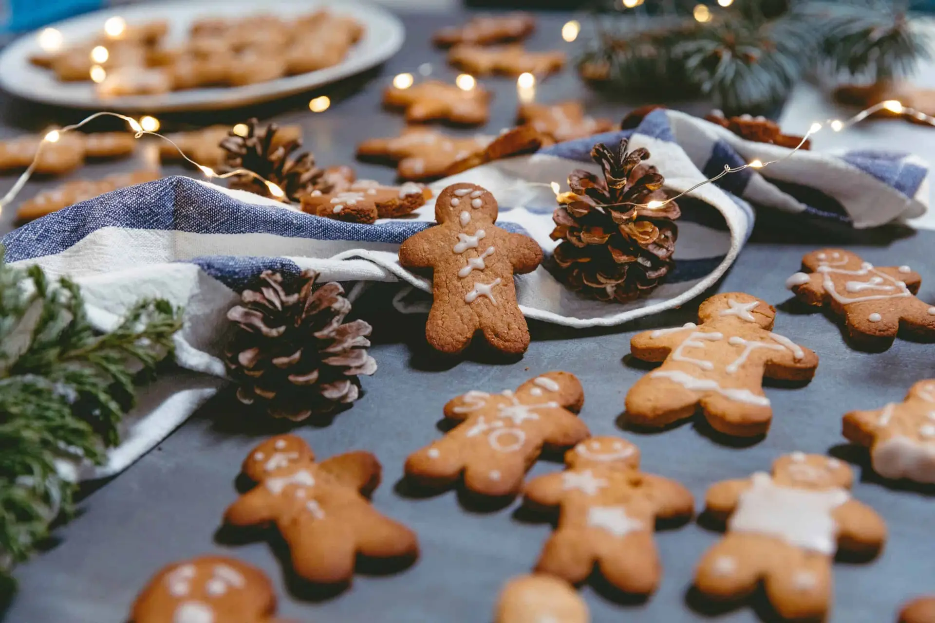 gingerbread cookies arranged on table with lights and pinecones as part of a holiday food spread