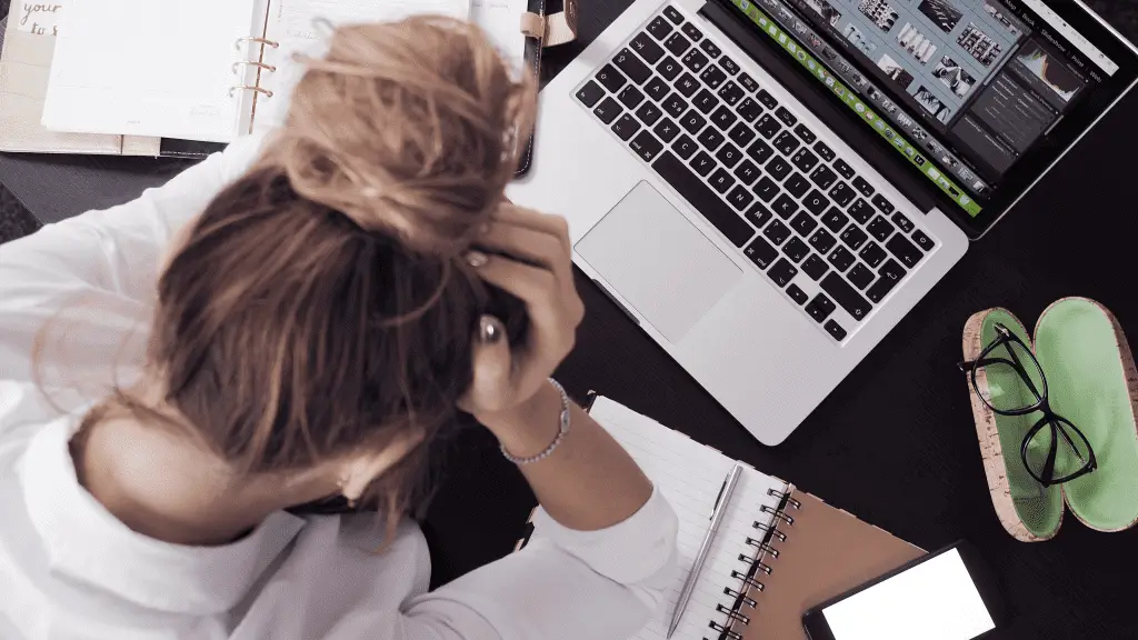 stressed out woman in front of laptop experiencing imposter syndrome