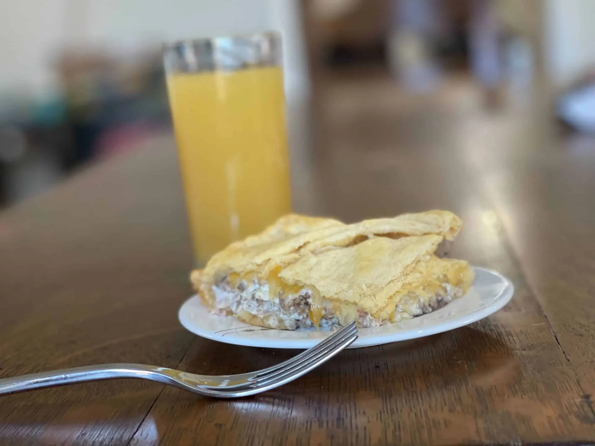 serving of sausage cream cheese casserole next to a glass of orange juice