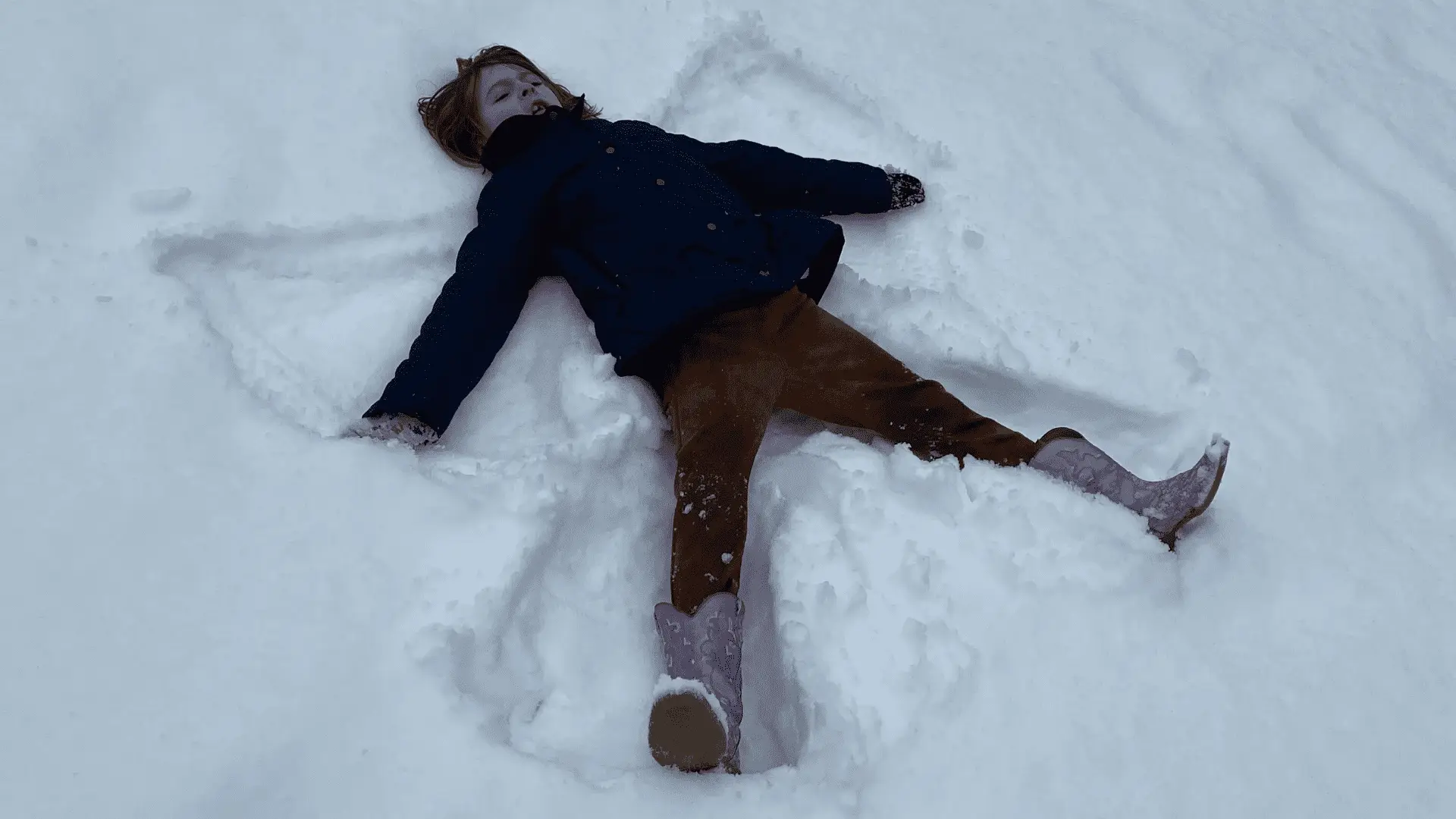 young boy making a snow angel as part of snow day activities