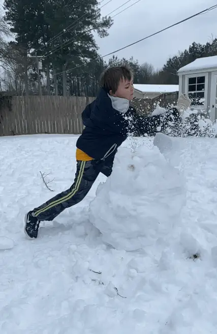 young boy destroying a snowman in slow motion 
