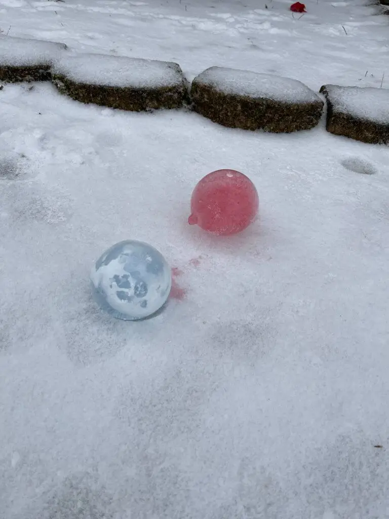 colorful ice balloons laying on snowy ground
