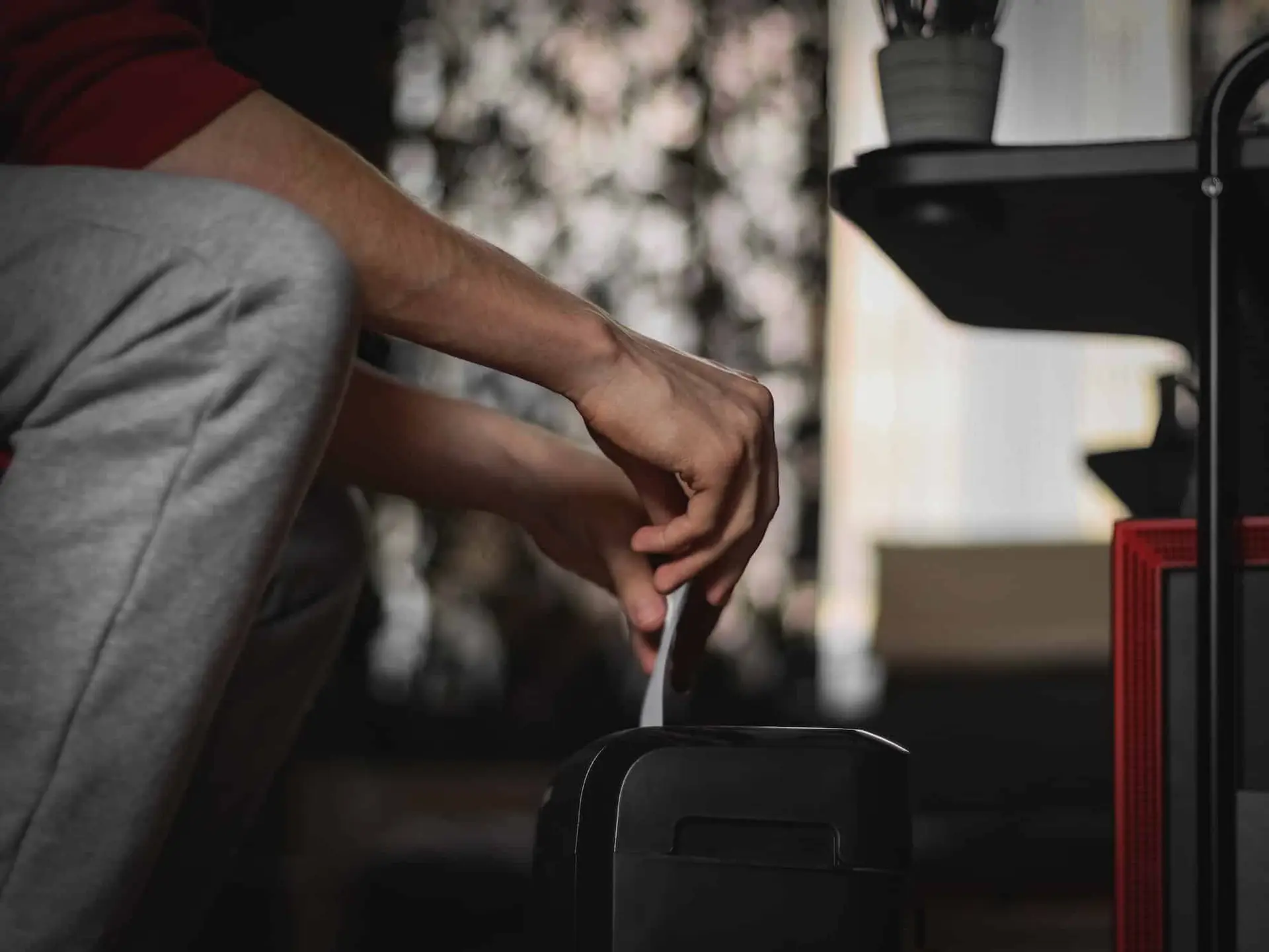 A caucasian young man is destroying documents in a black shredder